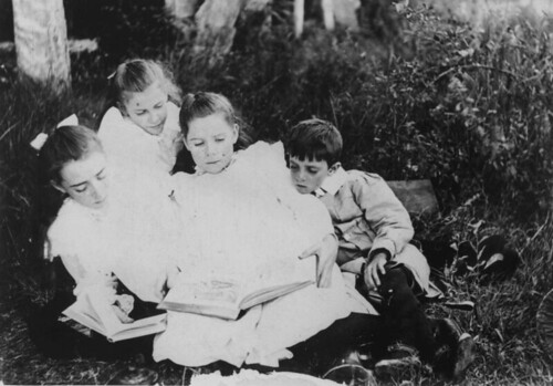 Group of children sitting on the grass reading...