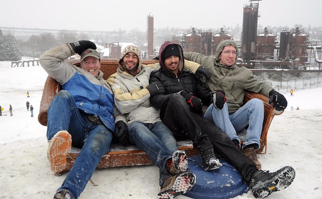 Smiling and celebrating, 4 guys in their sofa sled, couch surfing, winter wear, garbage can lid, on top of the hill, snow day, Gasworks Park, Wallingford, Seattle, Washington, USA