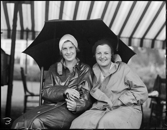Marjorie Morrill, left, and Betty Nuthall watch match in pouring rain at Essex Country Club, Manchester-by-the-Sea