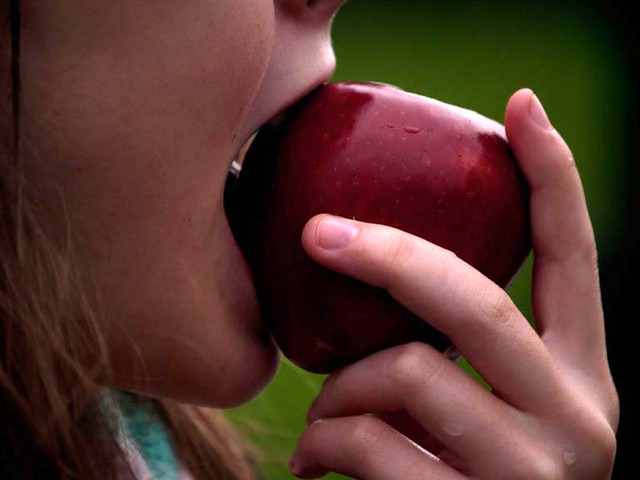 girl eating red apple