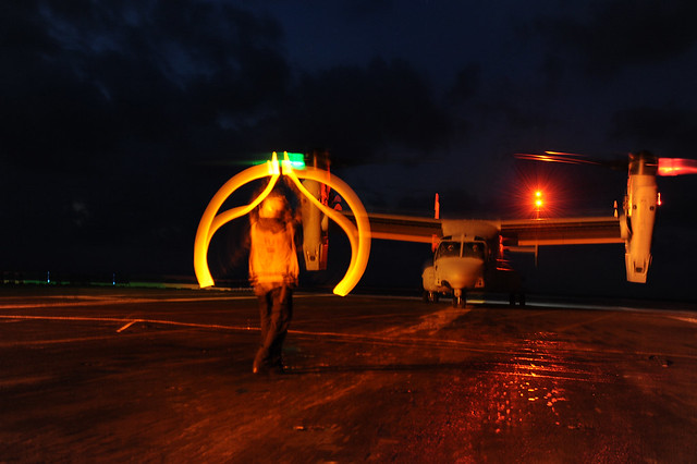 A Sailor directs the landing of an Osprey.