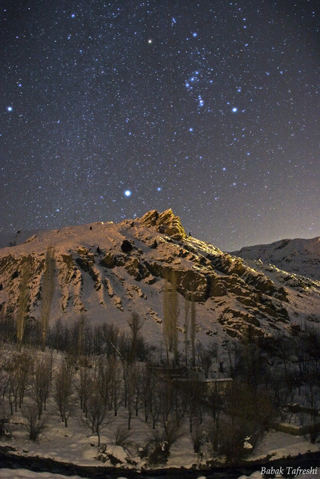Сириус (самая яркая звезда) и созвездие Ориона над покрытым снегом ландшафтом горного хребта Эльбурс.