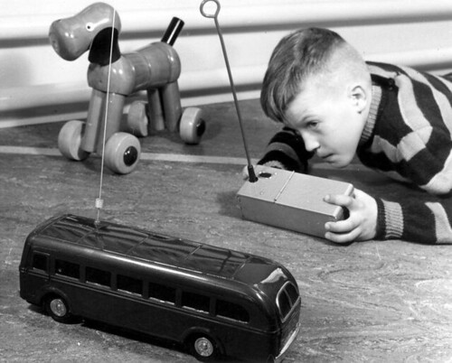 Jongetje speelt met radiografisch bestuurde speelgoedbus / Boy  playing with a radio-controlled toy bus