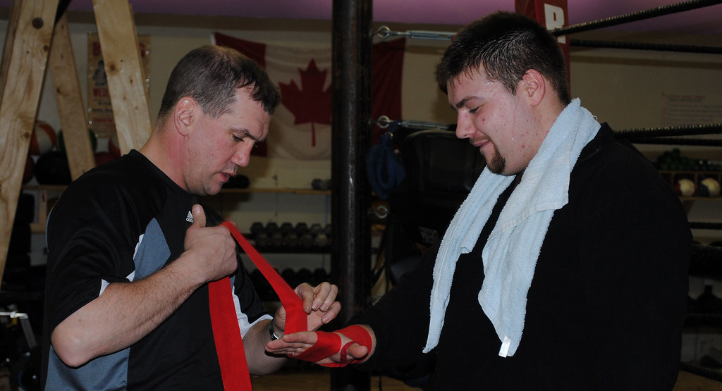 Coach Stuart McGrandle helps a boxer put his hand wraps on