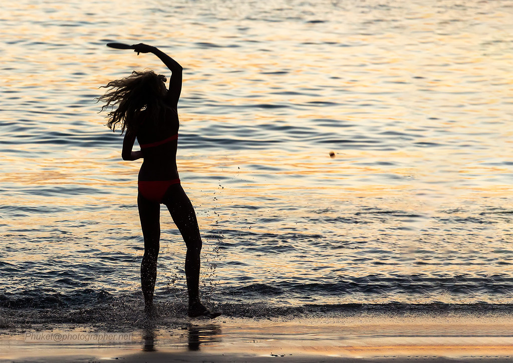 : Silhouette of girl playing ball. Phuket island, Thailand                     XOKA9905bs