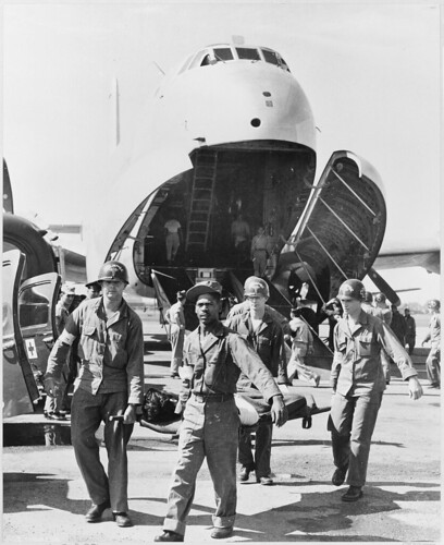 Army medics carry wounded UN personnel to waiting ambulances, after the patients' arrival at this Tokyo base in the U.S. Air Force C-124 in the background. ©  Robert Sullivan