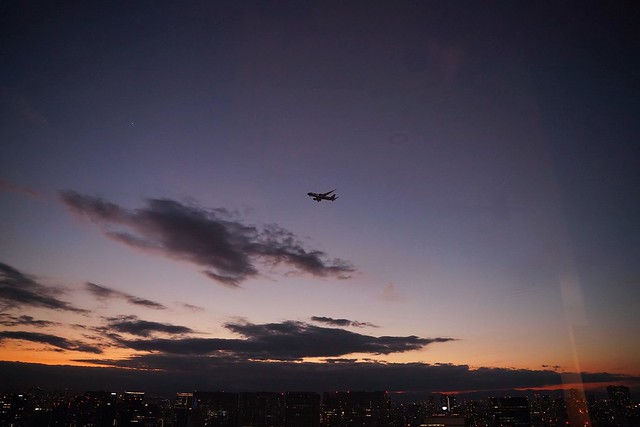 窓から見える夕焼けに飛行機のシルエットが...