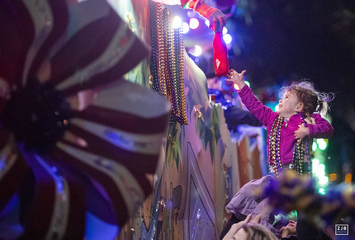Jenna Fritscher lifts up Jeri Lynn, 3, to get a plush toy during her first Mardi Gras on Sunday, Mar